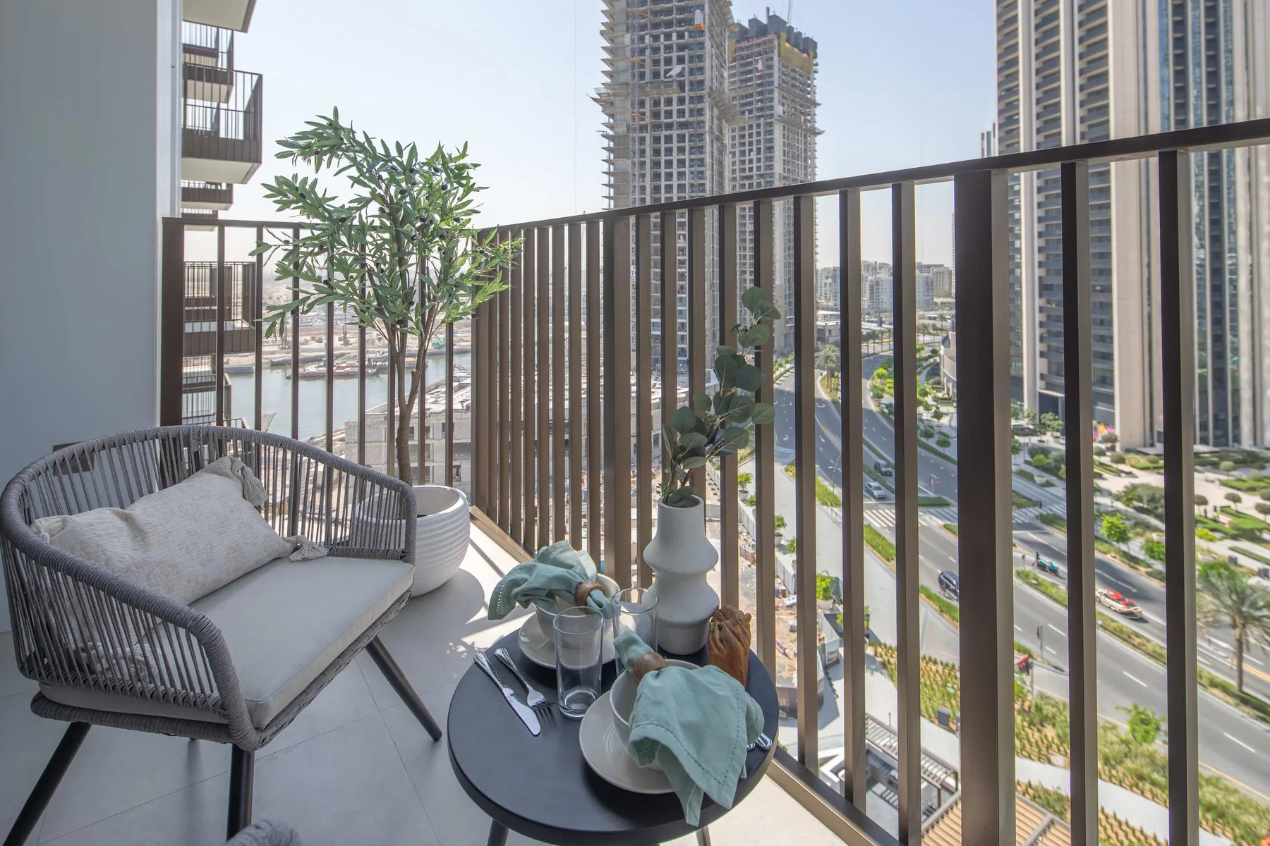A balcony seating area with a small table overlooks a city street.