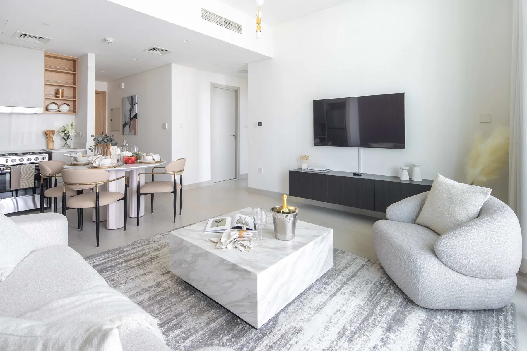 Una sala luminosa con televisor, asientos y un comedor.