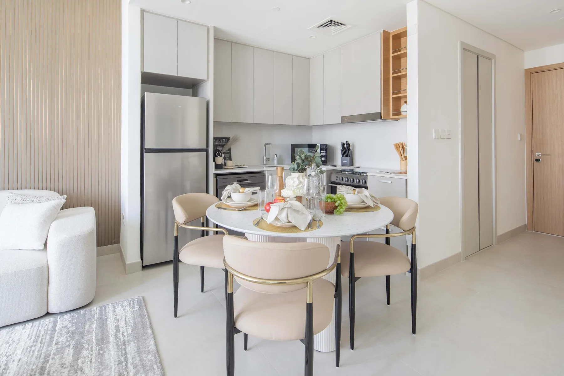 A bright dining area with a round table beside an open kitchen.
