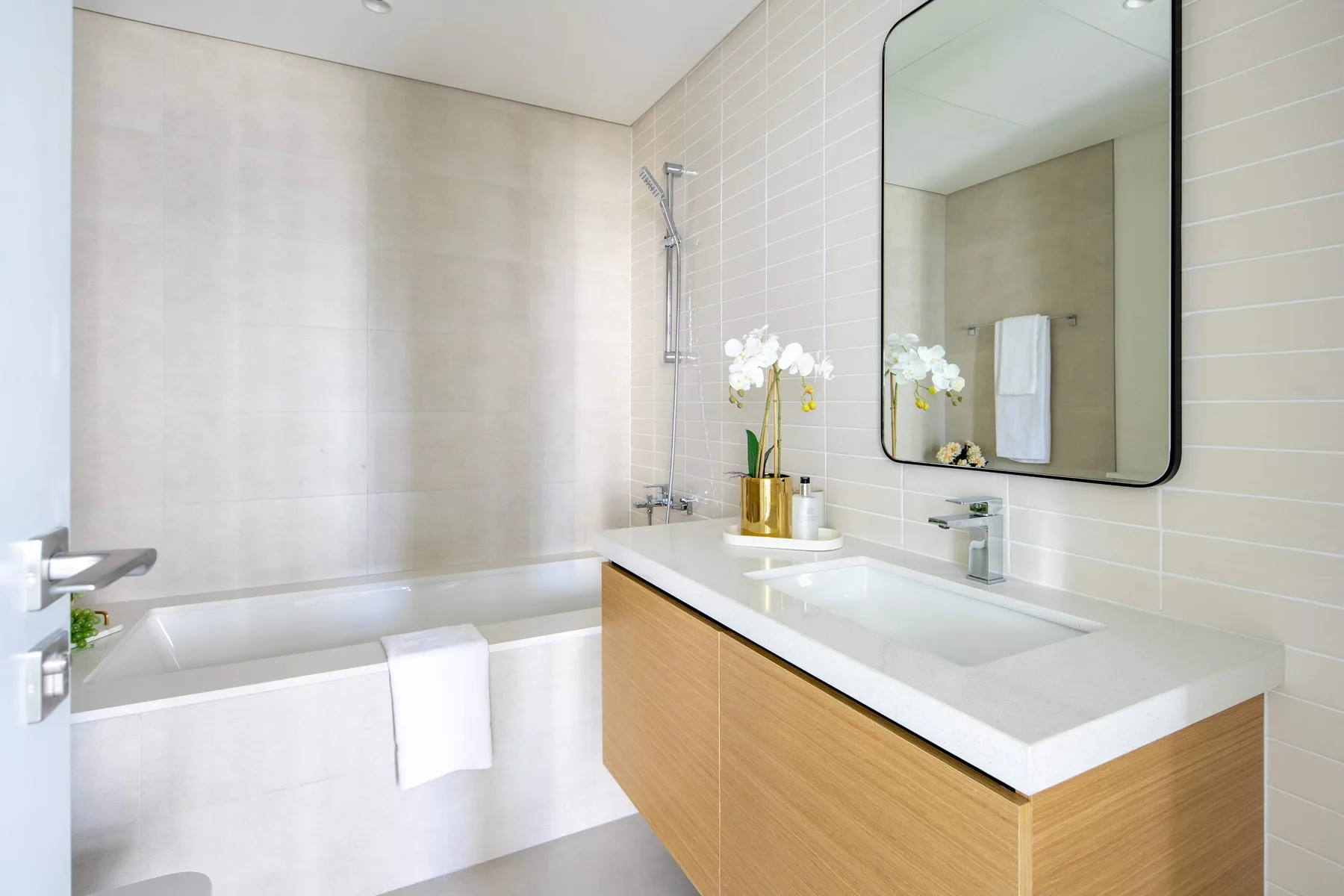 A bright bathroom with a bathtub, vanity, and wall mirror.