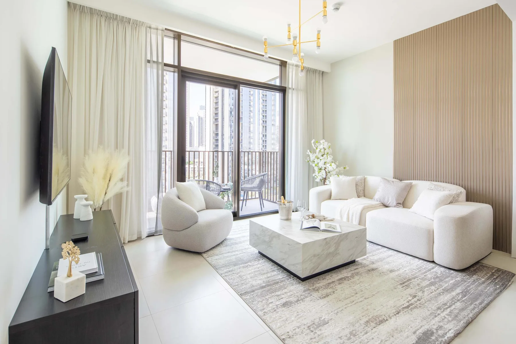 A bright living room with a sofa and large windows opening onto a balcony.