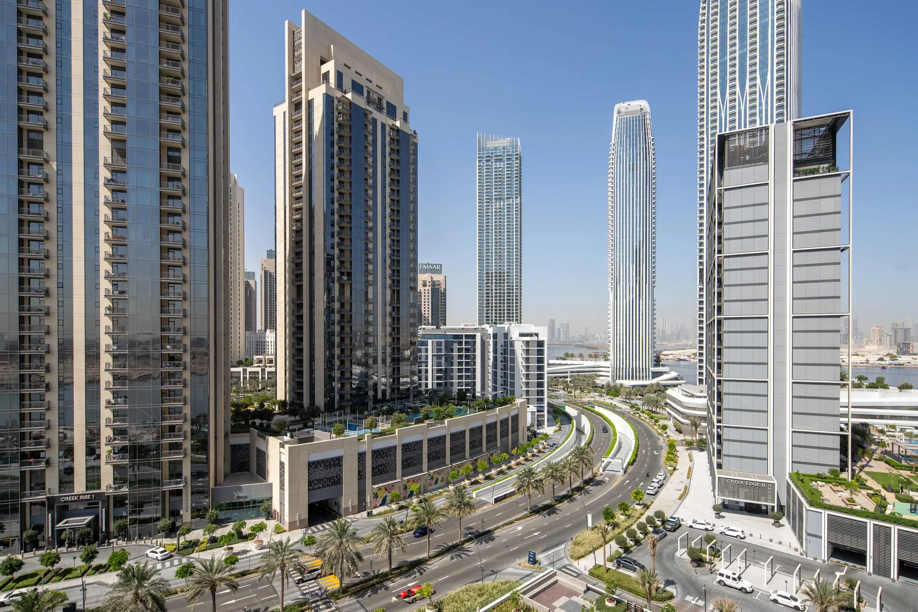 A city skyline of tall buildings beside a curving road.
