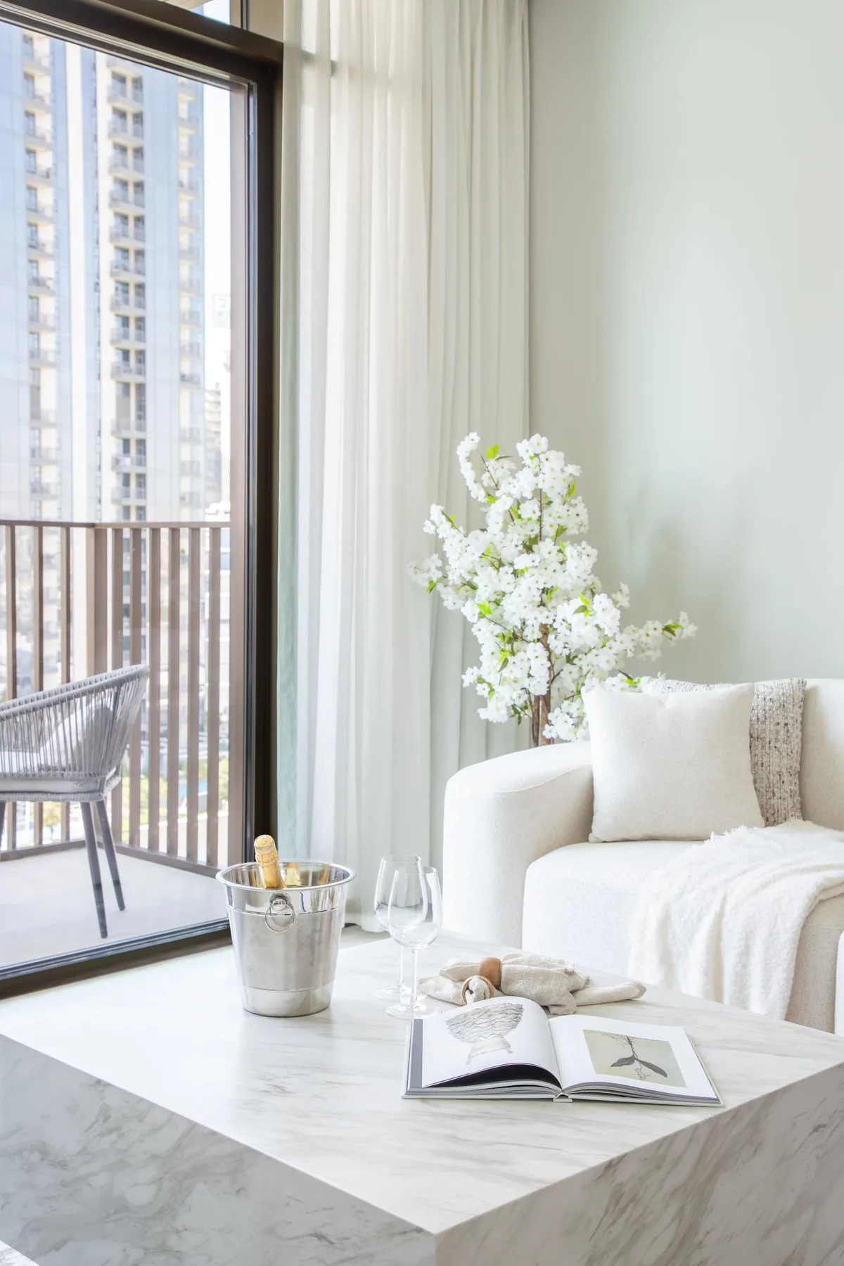 A bright living room with a white seating area beside a large window.