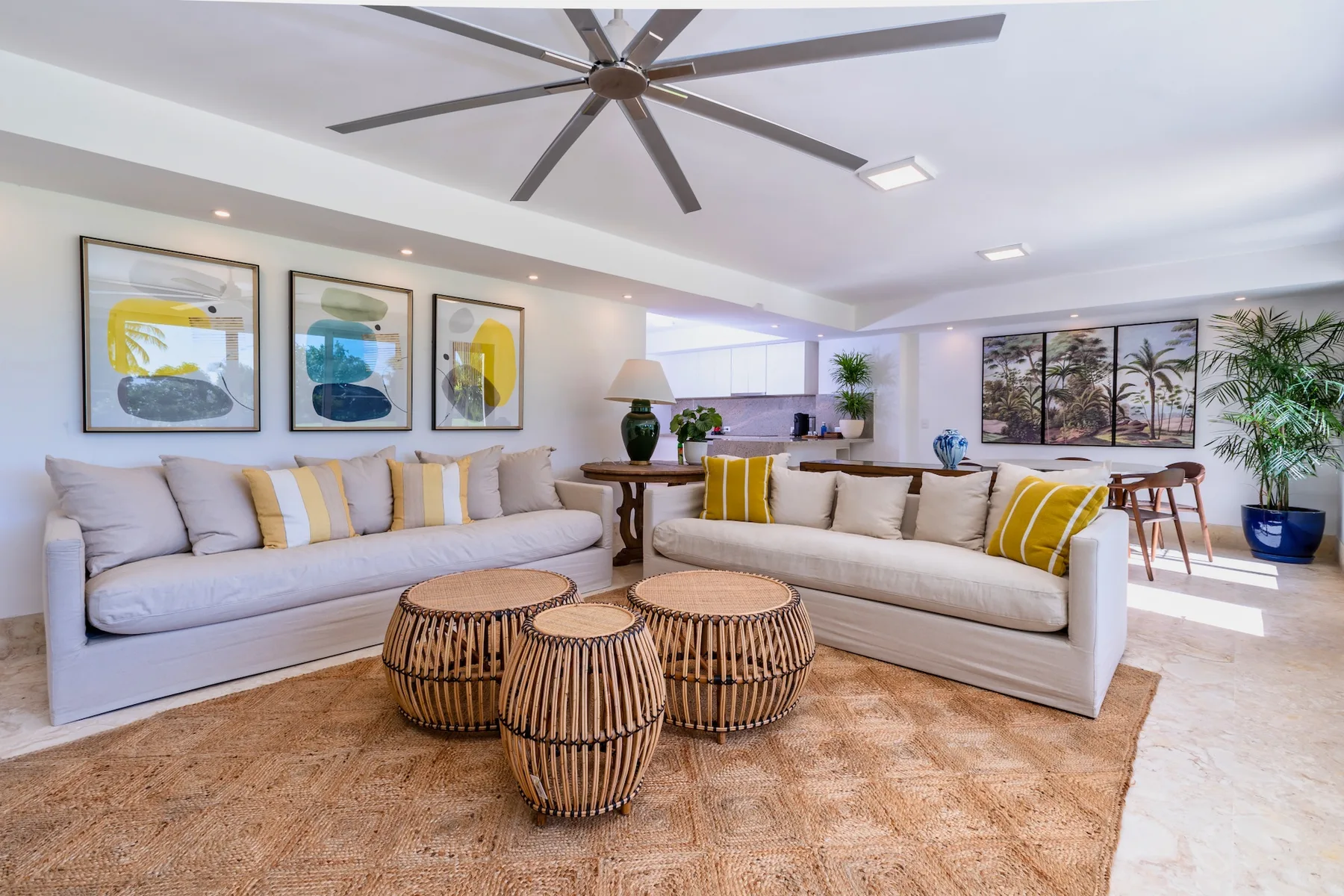A bright living room with seating, round tables, and large windows.