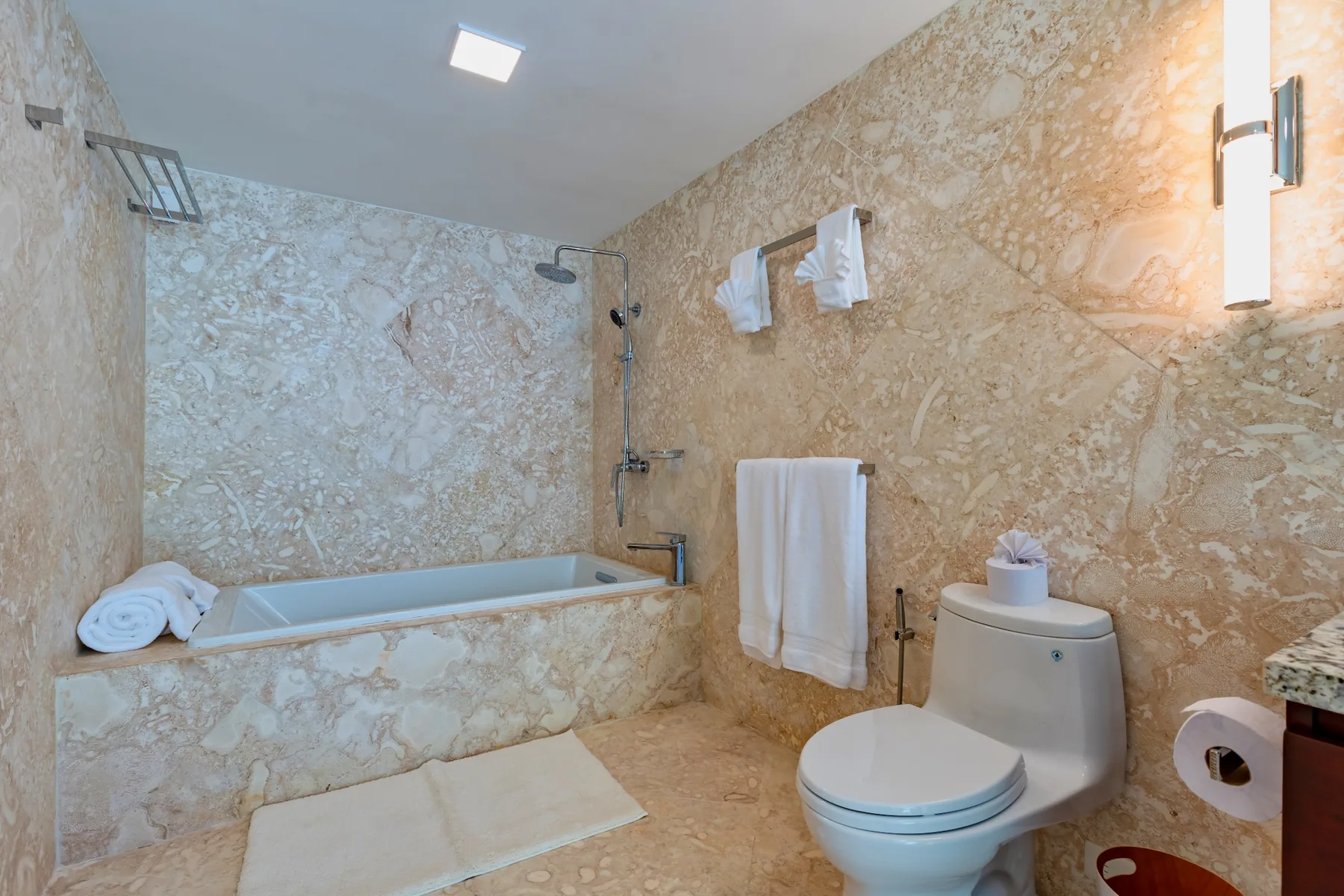 A bathroom with a bathtub, shower, toilet, and towels.