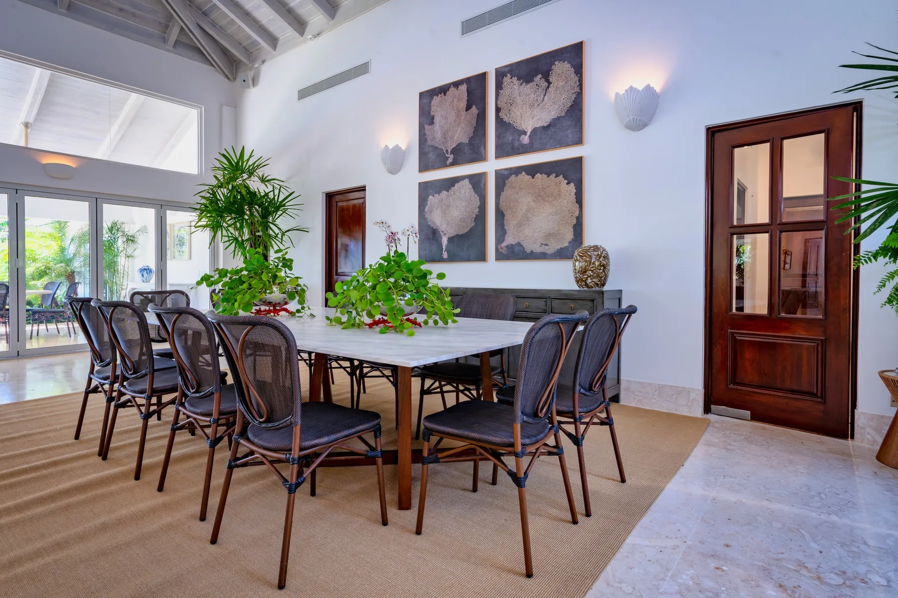 A dining room with a long table and chairs beneath framed wall art.