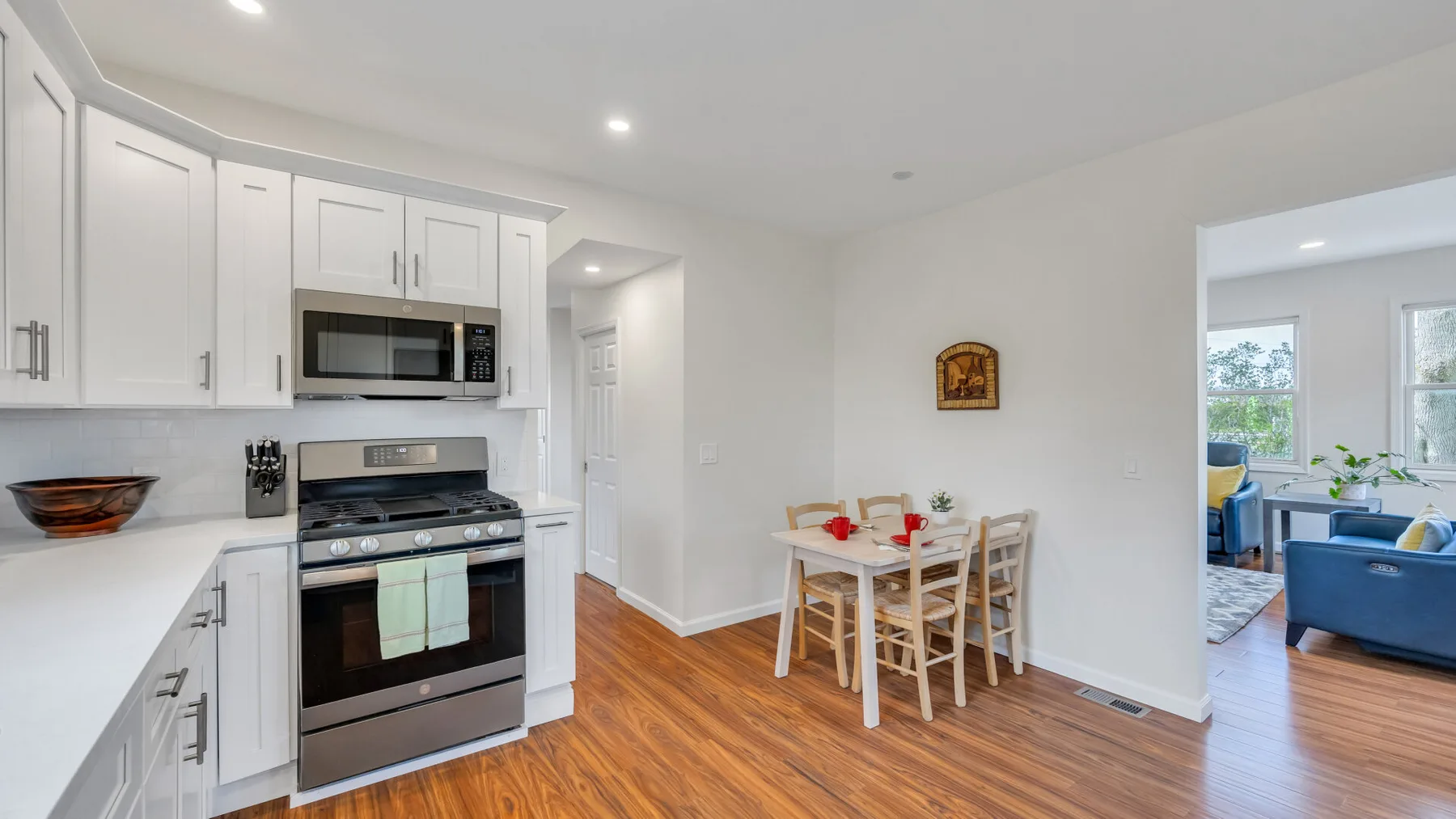 A bright kitchen and dining area with white cabinetry, stainless steel appliances, and a table.