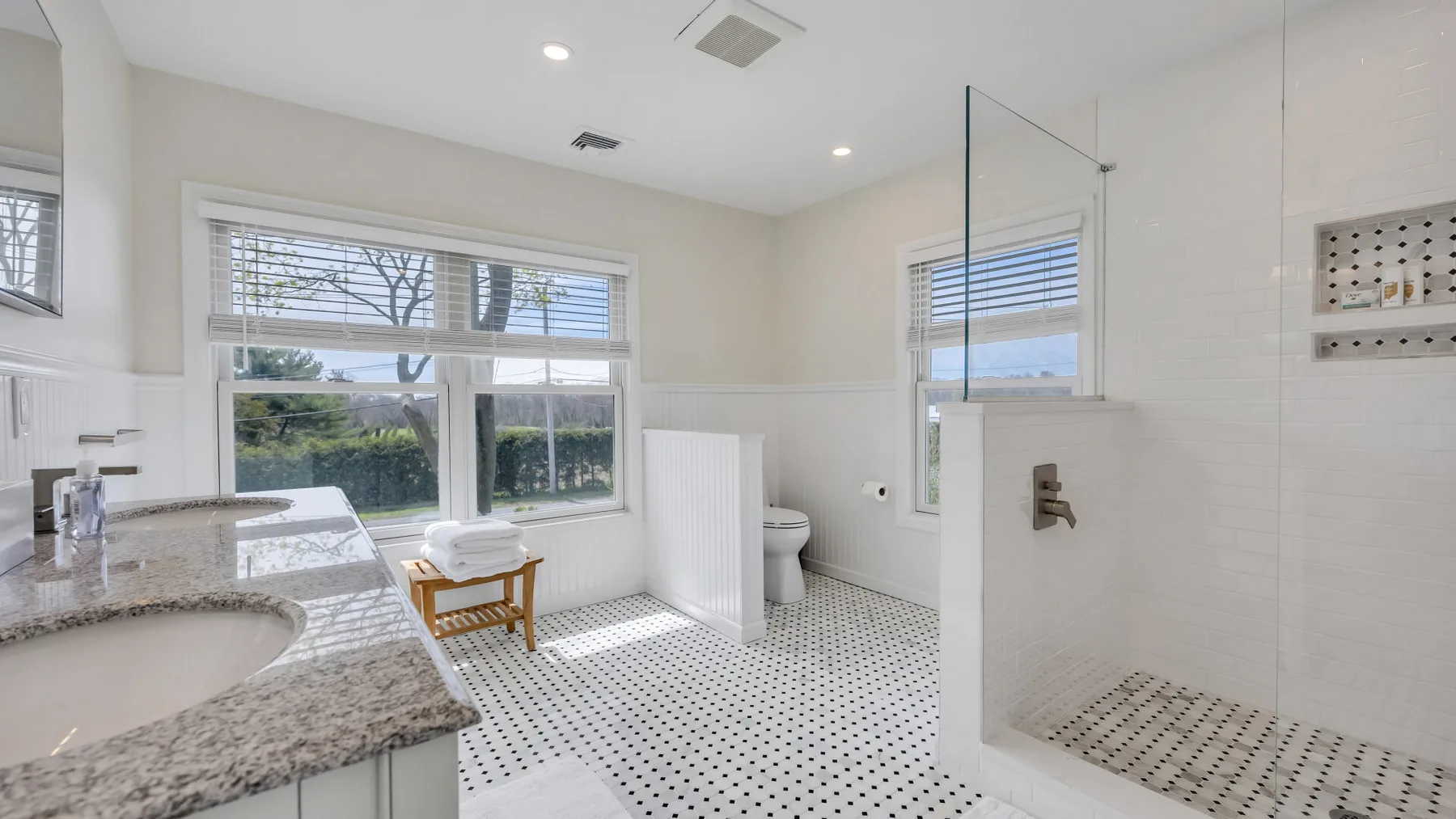 A bright bathroom with a long vanity and a glass shower area.
