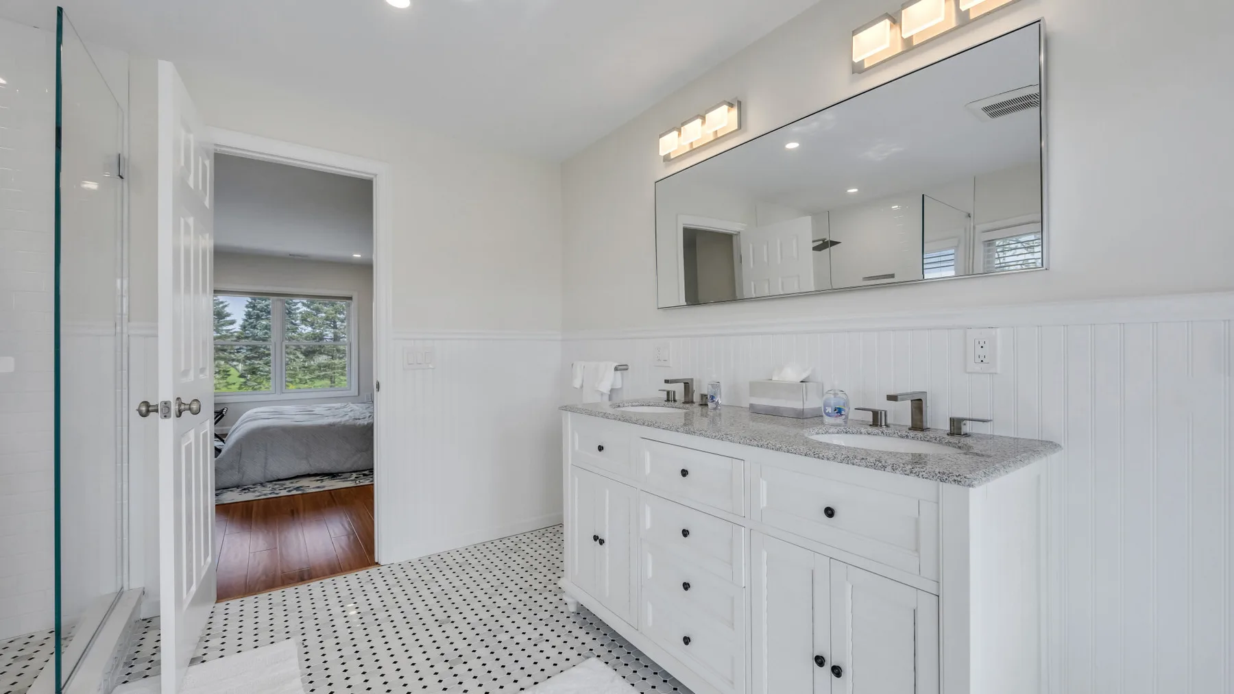 A bright bathroom with a long vanity and large mirror.