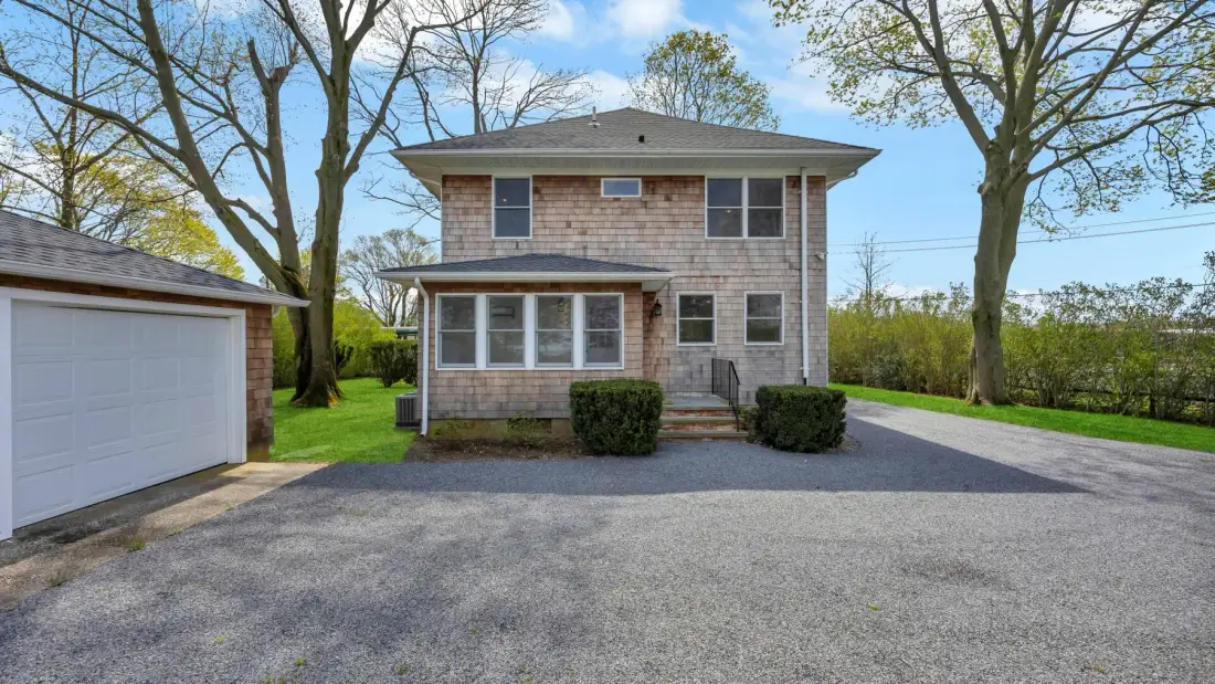 A two-story house with a paved driveway and detached garage.