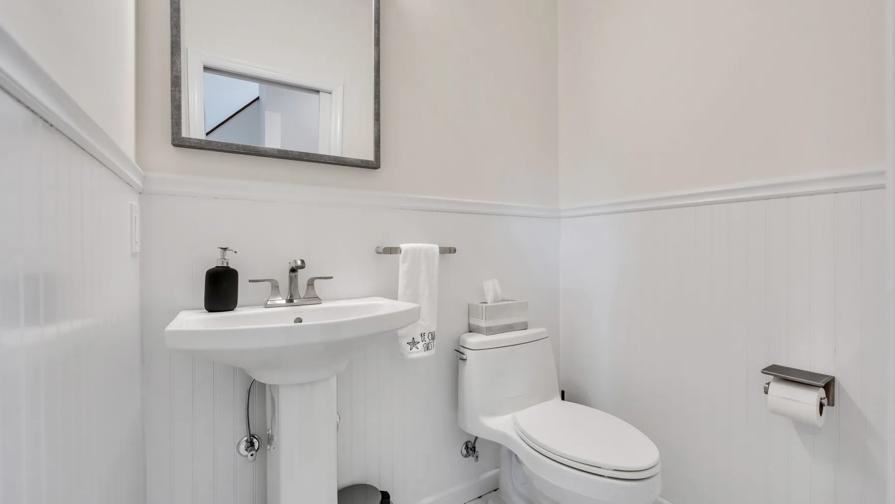 A bright bathroom with a sink, toilet, and wall mirror.