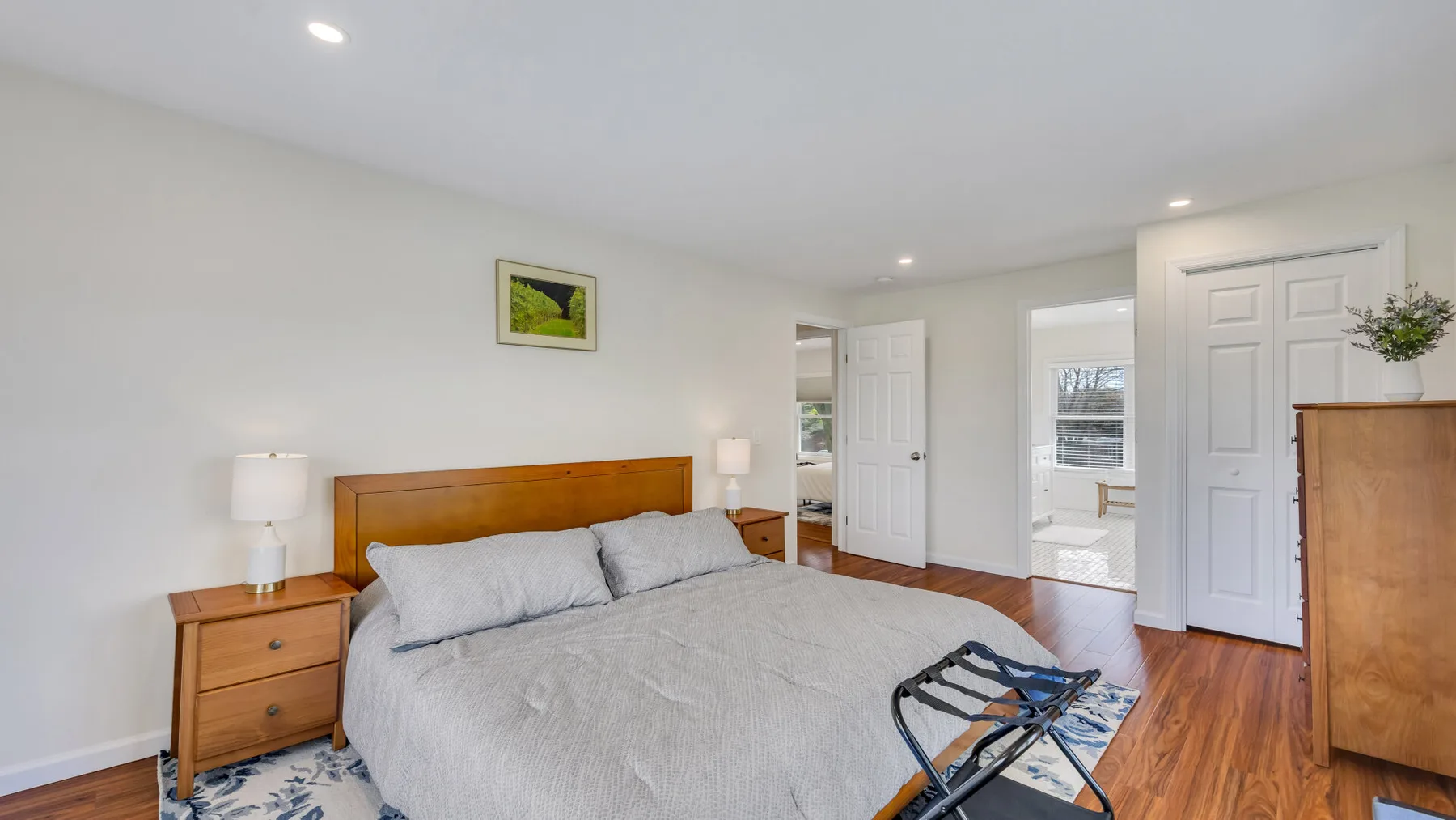 A bedroom with a bed, wooden bedside tables, and hardwood flooring.
