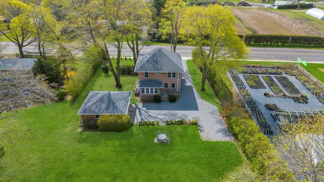 Aerial view of a brick house, lawn, and adjoining garden plots.