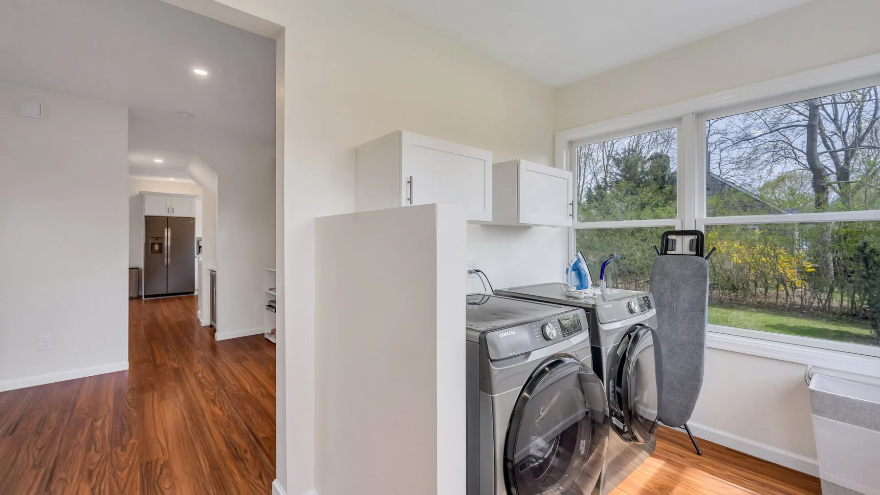A laundry area with front-loading appliances beneath wide windows.
