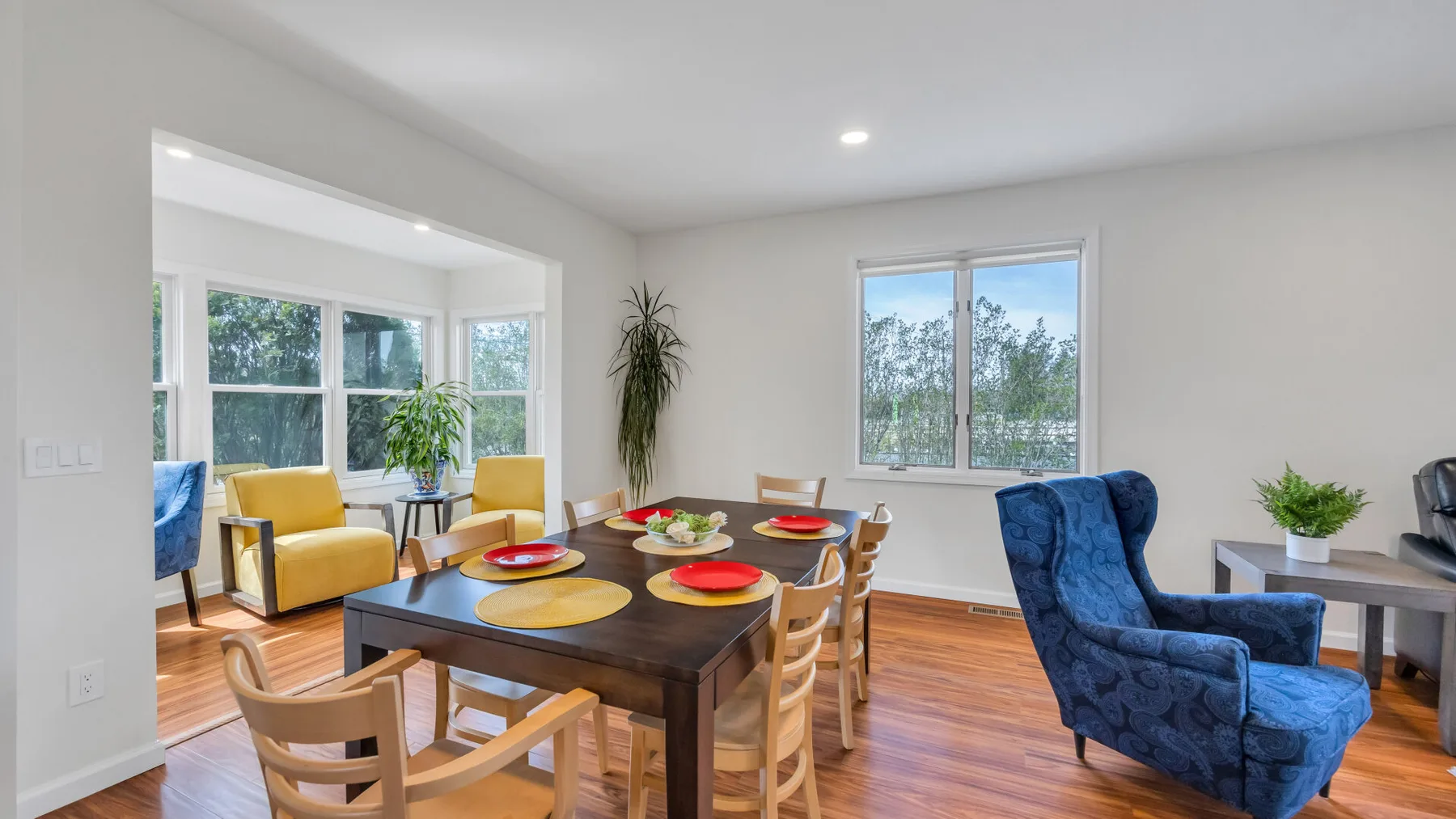 A bright dining and seating area with a wooden table and blue armchair.