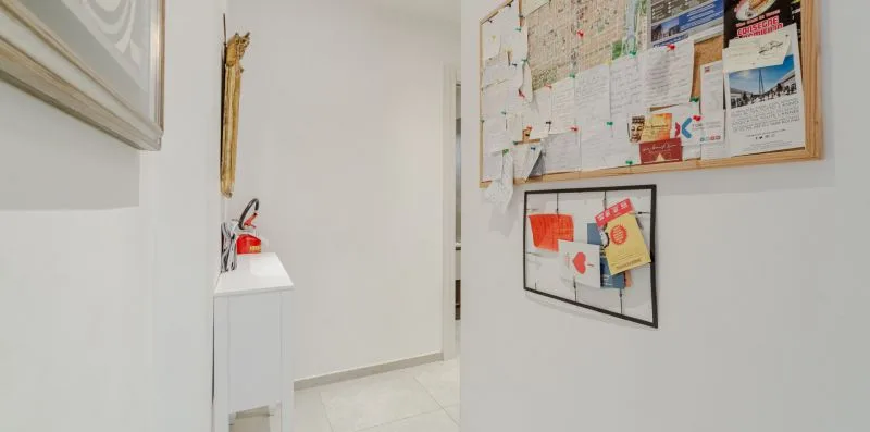 A white hallway with bulletin boards displaying assorted papers and notices.