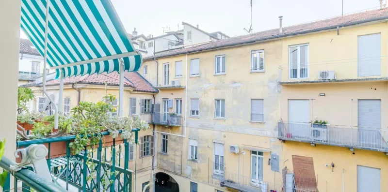 A balcony overlooks a courtyard of pale yellow residential buildings.