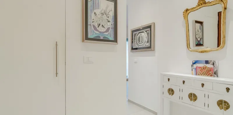 A bright hallway with framed artwork and a decorative wall mirror.