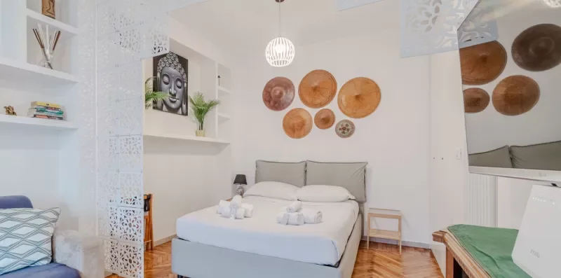 A bright bedroom with a bed, wall art, and built-in shelves.