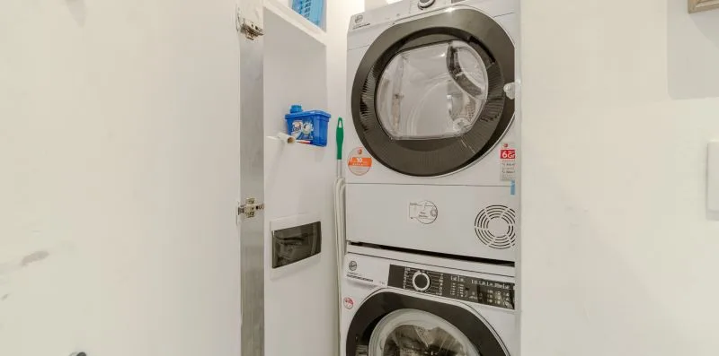 A laundry area with a stacked washer and dryer inside a cabinet.