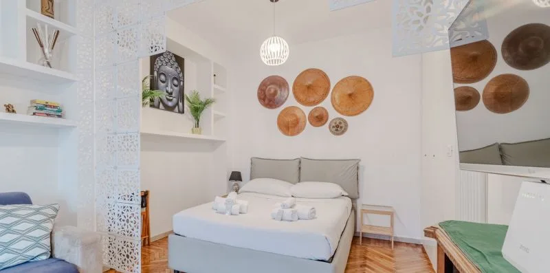 Un dormitorio luminoso con una cama, platos decorativos en la pared y estantes abiertos.