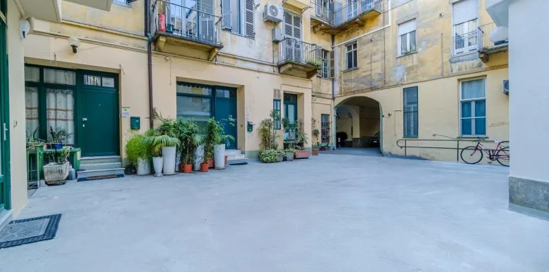 A paved courtyard surrounded by apartment buildings, with potted plants near the entrances.