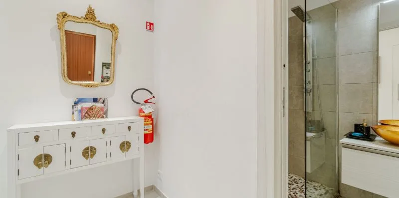 A bathroom vanity and mirror stand beside a glass shower.