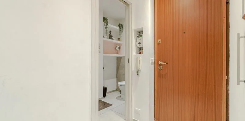 A bathroom is visible through the open doorway beside a wooden entry door.