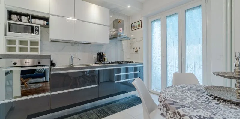 Una cocina moderna con comedor, armarios brillantes y un mantel estampado.