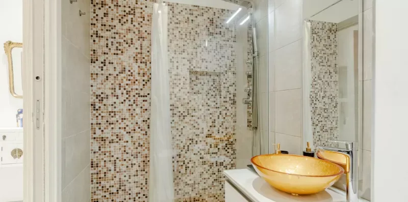 A tiled shower area with a sink and a large bowl-shaped basin.