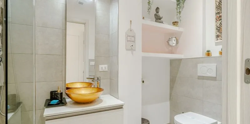 A tiled bathroom vanity with a vessel sink, mirror, and toilet.