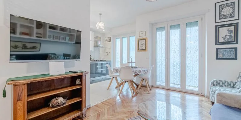 A bright dining and sitting area with a table beside tall glass doors.