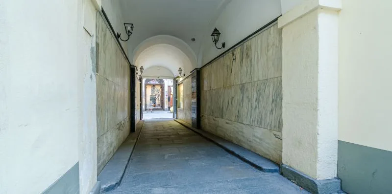 A covered passageway with stone walls and a bright opening at the far end.