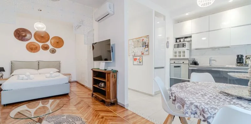 A bedroom with a bed and television opens onto a compact kitchen.