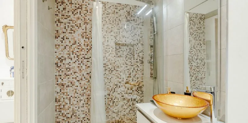 A bathroom with a glass shower and a vessel sink.