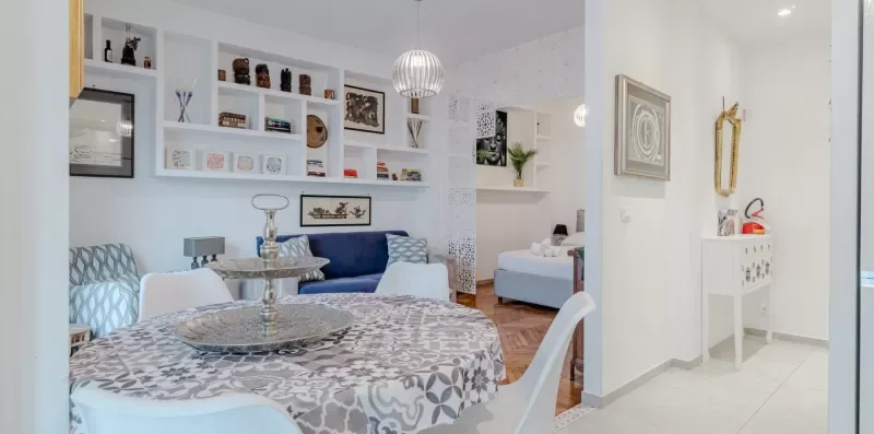 A bright living and dining area has a patterned table and blue seating.