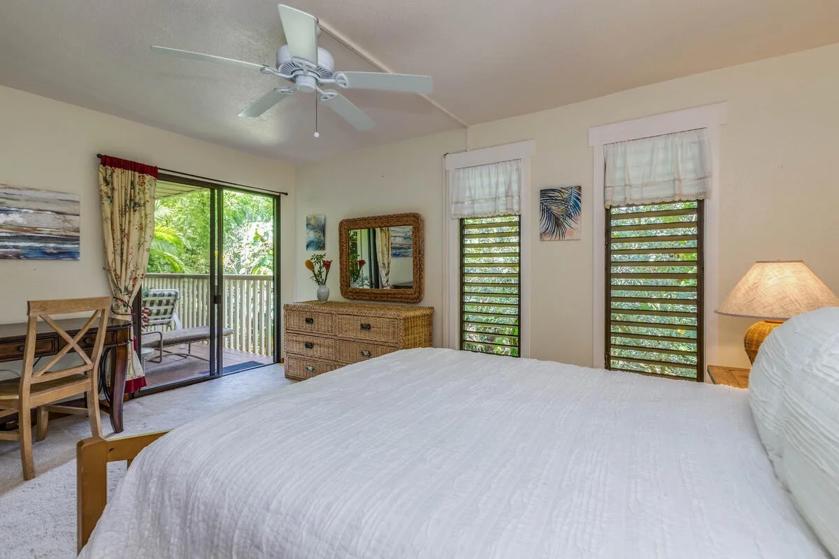 Un dormitorio con una cama, una cómoda y ventanas con vista a la vegetación.