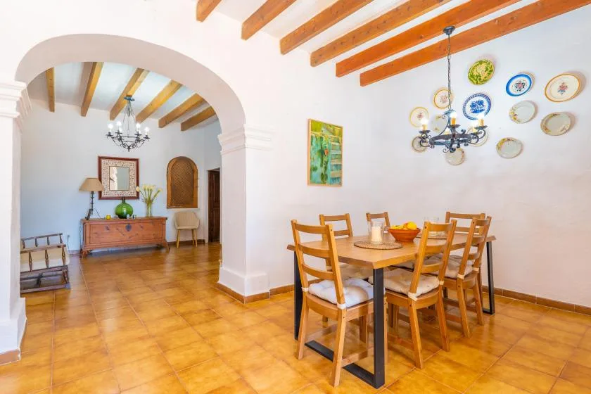 A dining area with a wooden table and chairs beneath exposed ceiling beams.