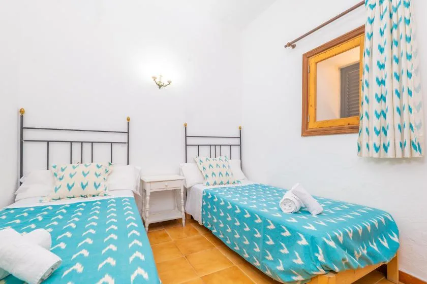 A bedroom with two beds covered in turquoise patterned bedding.