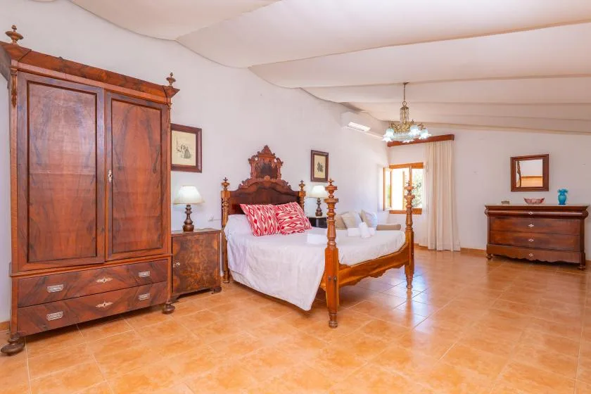 A bedroom with a wooden bed, wardrobe, and dresser.