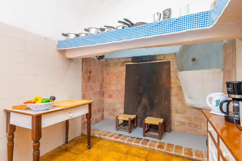 A rustic kitchen area with a brick hearth and a small worktable.