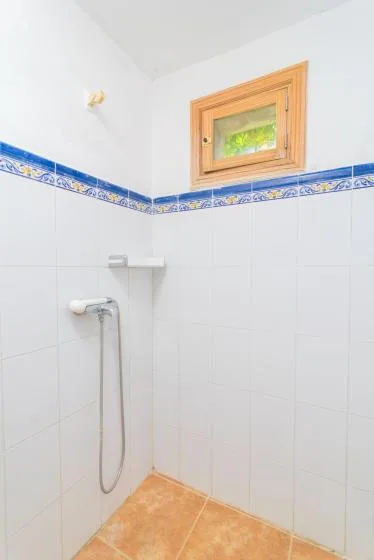 A tiled shower area with a decorative blue border and a small window.