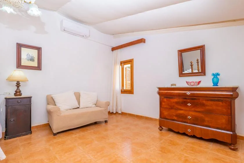 A furnished room with a beige sofa and a wooden dresser.