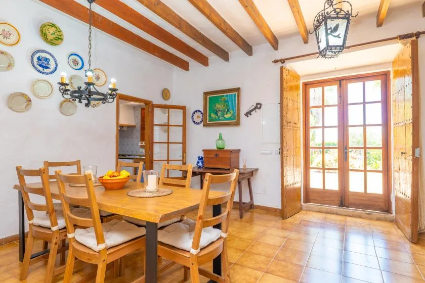 A dining room with a wooden table, chairs, and glass-paneled doors.