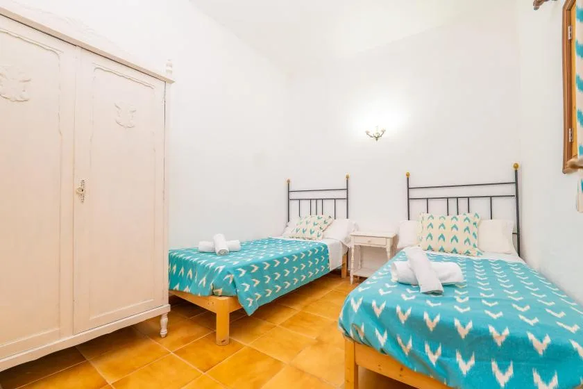 A bright bedroom with two beds covered in turquoise patterned bedding.
