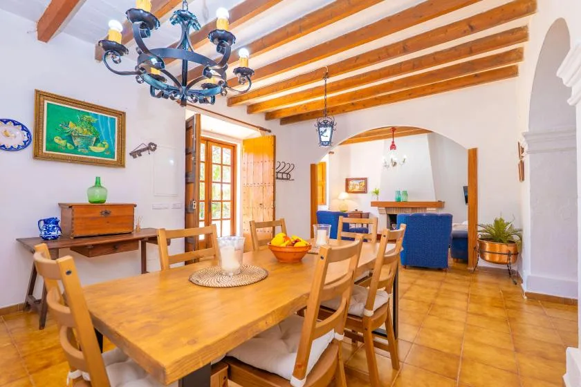 A dining room with a wooden table and chairs beneath exposed ceiling beams.