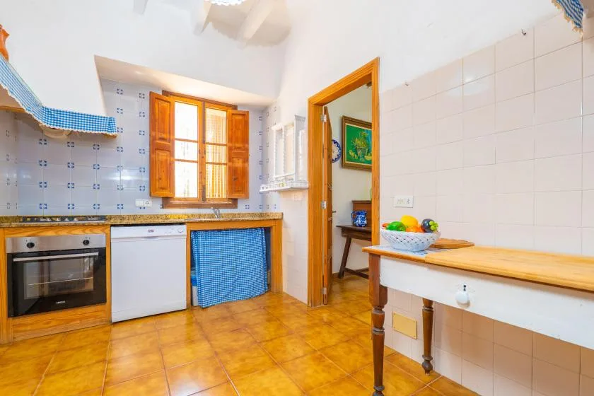 A tiled kitchen with wooden cabinets, a window, and a counter.