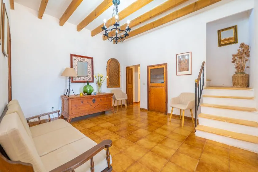 A bright interior entry hall with a wooden dresser and staircase.
