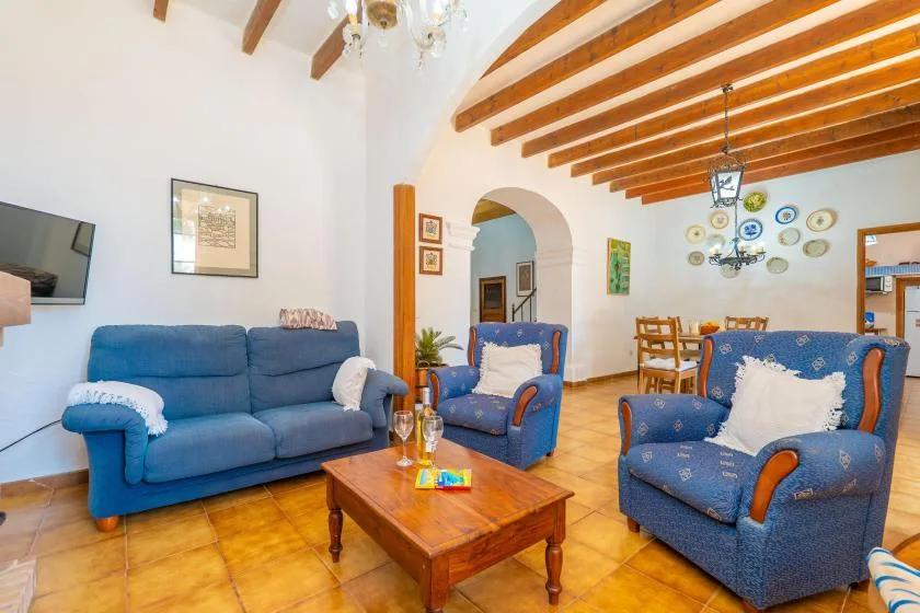 A living room with blue seating, a wooden coffee table, and exposed ceiling beams.