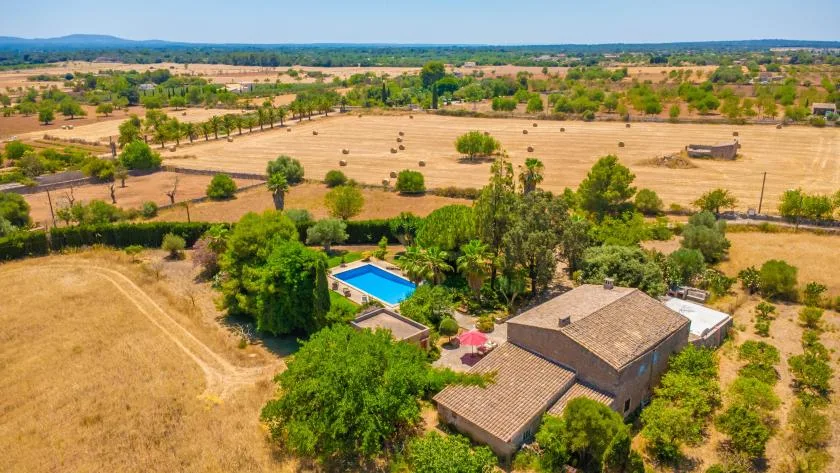 An aerial view of a rural property with a house, swimming pool, and surrounding fields.